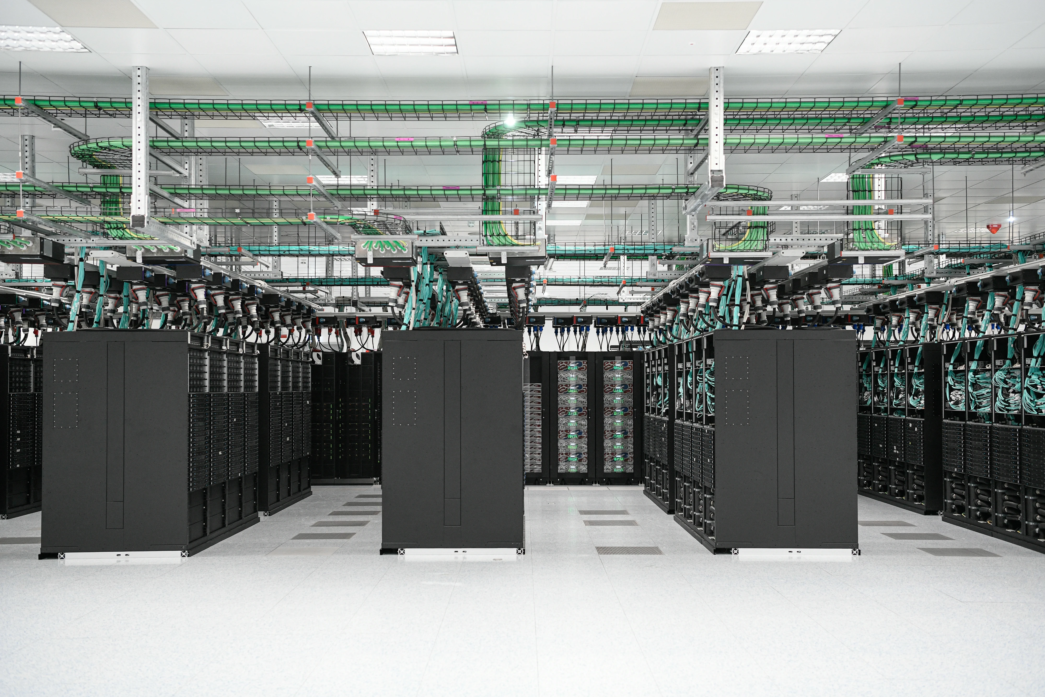 Sala di un centro di supercalcolo con file di rack illuminate da apparecchi LED lineari sull'asse dei corridoi